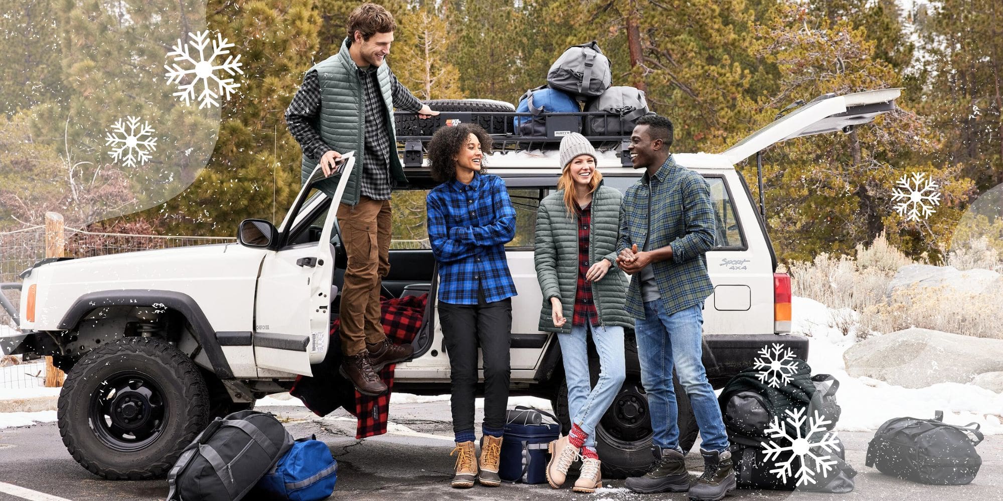 Four people wearing custom apparel and standing in front of other branded holiday gifts around an SUV. There is snow, rocks, and evergreen trees behind them.