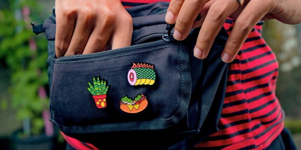 Colorful enamel pins attached to a bag, showing how collectible pins can be worn and displayed in everyday branded merchandise
