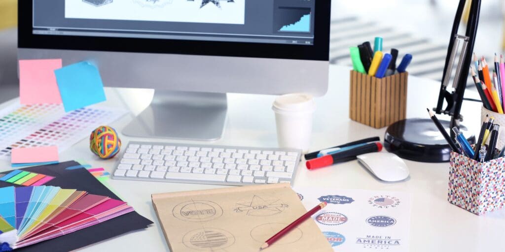 Graphic design workspace with color samples, logo sketches, and branded artwork used to develop promotional product designs.