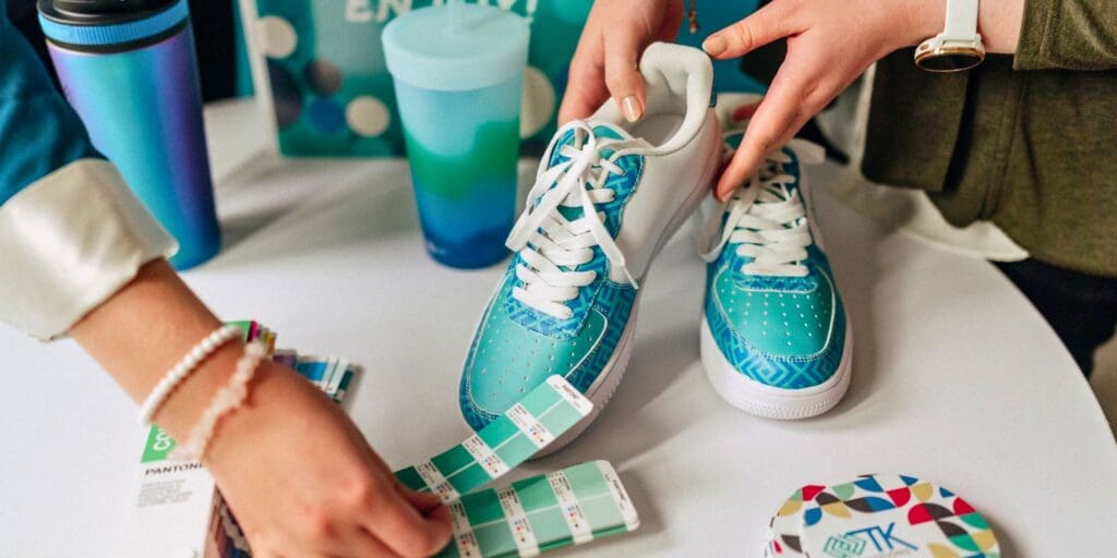 Promotional product design process using Pantone color swatches to coordinate branded shoes and drinkware.